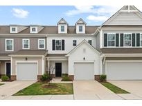 View of townhome exteriors showing the garages and small landscaped front lawns under a cloudy blue sky at 95 Little Leaf Lane Ln, Clayton, NC 27527