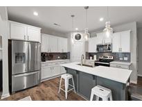 Well-lit kitchen features stainless steel appliances, gray backsplash, and a large kitchen island with seating for two at 95 Little Leaf Lane Ln, Clayton, NC 27527