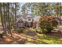 Beautiful brick two-story home with lush landscaping, mature trees, and a welcoming front entrance at 101 Preston Arbor Ln, Cary, NC 27513