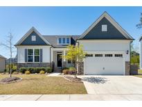 Charming home with a two-car garage, stone accents, manicured lawn, and beautiful landscaping at 1165 Saint Cloud Loop, Apex, NC 27523