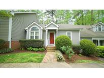 Charming home featuring a bright red front door, brick walkway, and well-maintained landscaping at 1415 Quarter Pt, Raleigh, NC 27615