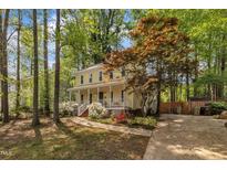 Charming yellow two-story home featuring a cozy front porch and lush landscaping at 1600 S Wade Ave, Garner, NC 27529
