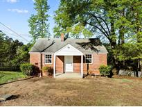 Charming brick home featuring a cozy front porch and mature trees at 203 W Pilot St, Durham, NC 27707