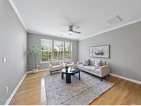 Bright living room with modern furniture, a ceiling fan, and large windows allowing ample natural light at 4210 Brynwood Ave, Durham, NC 27713