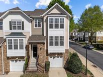 Charming townhome featuring a stone facade, attached garage, and a well-maintained lawn at 5702 Cameo Glass Way, Raleigh, NC 27612