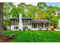 Charming two-story home featuring an olive green facade, white accents, and a neatly manicured lawn with mature trees at 7409 Fiesta Way, Raleigh, NC 27615