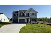 Charming two-story home with a three car garage and a well-manicured lawn under a bright blue sky at 87 Heatherglenn Cir, Princeton, NC 27569