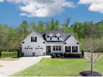 Charming two-story white farmhouse with black shutters, three-car garage, and lush green lawn at 9220 Yardley Town Dr, Wake Forest, NC 27587