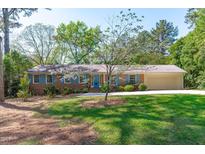 Charming one-story brick home with blue shutters, lush lawn, and mature flowering tree at 1005 Greenwood Cir, Cary, NC 27511