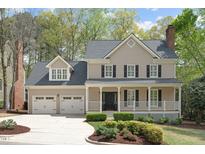 Charming two-story home featuring a covered front porch, well-manicured landscaping, and a two-car garage at 102 Parkbranch Ln, Cary, NC 27519