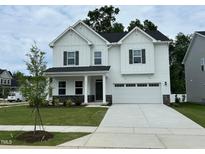 Beautiful white two-story home featuring a covered porch, well-manicured lawn, and a two-car garage at 1572 Bright Coral Trl, Wendell, NC 27591