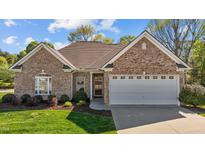 Charming brick home featuring a well-manicured lawn, arched window and attached two-car garage at 252 Shea Ct, Graham, NC 27253