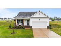 Charming single-Gathering home with a well-manicured lawn and a welcoming front porch with chairs at 295 Springtooth Dr, Zebulon, NC 27597