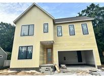 Two-story yellow home with black frame windows and an attached garage under construction at 406 Columbia Dr, Raleigh, NC 27604