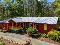 Charming red home with a metal roof, inviting porch, and landscaped front yard at 5401 Friends School Rd, Durham, NC 27705