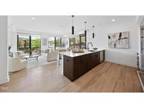 Open concept kitchen with wood floors, island, stainless steel appliances, pendant lights, and living space at 615 W Peace St # 201, Raleigh, NC 27605