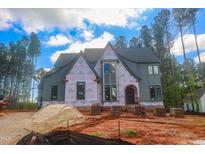 New two-story home under construction, featuring gray siding, brick base and an arch entryway at 7436 Summer Tanager Trl, Raleigh, NC 27614