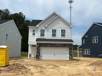 Two-story home with white siding, black roof, and two-car garage featuring stone facade on an unfinished lot at 752 Swim Cave Ln, Wendell, NC 27591