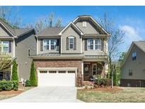 Charming two-story home featuring a stone and siding exterior with a two-car garage and manicured lawn at 936 Regency Cottage Pl, Cary, NC 27518