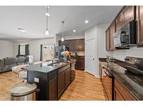 A kitchen boasts a central island with barstool seating and sleek, modern appliances on wood-look floors at 95 Shady Creek Trl, Garner, NC 27529