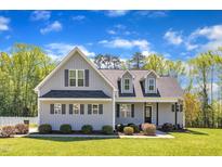 Charming two-story home with gray siding, a black roof, and well-manicured landscaping at 1077 Williams-White Rd, Zebulon, NC 27597