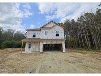 Two story house during construction with wood and Tyvek, attached two car garage, and forested background at 136 Baneberry Pl, Broadway, NC 27505