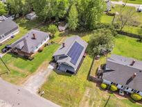 An aerial view of a well maintained home with solar panels on the roof and a spacious grassy yard at 303 E J St, Erwin, NC 28339