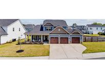 Charming home featuring a three-car garage, landscaped yard, and cozy front porch with seating at 34 Tea Olive Ct, Clayton, NC 27520
