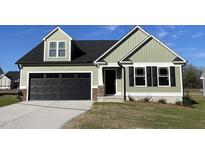 Charming home featuring sage vinyl siding, a black garage door, and tasteful stone accents at 37 Heatherglenn Cir, Princeton, NC 27569
