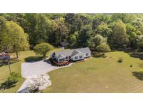 Expansive aerial view of home with manicured lawn, mature trees, and a cozy wraparound deck, perfect for outdoor living at 413 Bayles Rd, Lillington, NC 27546