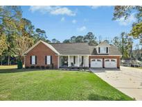 Charming brick home featuring a manicured front lawn, a two-car garage and inviting front porch at 460 Mann Rd, Coats, NC 27521