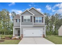Charming two-story home featuring a two-car garage, stone accents, and a well-manicured lawn at 601 Benton Dr, Oxford, NC 27565