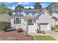 Charming two-story home features a white painted brick exterior, gabled roof, and manicured front yard at 8721 Attingham Dr, Raleigh, NC 27615