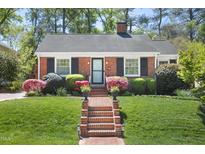 Charming brick home featuring a manicured lawn, brick walkway and lush landscaping at 1109 Huntington Ave, Durham, NC 27707