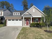 Charming home features a brick facade, two-car garage, manicured lawn, and a welcoming red front door at 120 Putters Ct, Durham, NC 27703