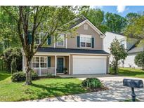 Charming two-story home featuring a 2-car garage, manicured lawn, and covered front porch at 12433 N Exeter Way, Durham, NC 27703