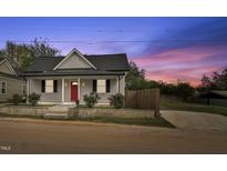 Charming single-story home featuring a red front door, grey siding, and well-maintained landscaping at 1284 Railroad St, Henderson, NC 27536