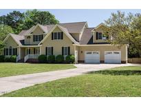Charming two-story home featuring a manicured lawn, two-car garage, and traditional architectural details at 2213 Ravens Creek Ct, Raleigh, NC 27603