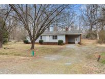 Quaint single story house with a gravel driveway, covered parking, and a brick chimney at 2670 Turner Rd, Mebane, NC 27302