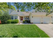 Charming home featuring a red front door, attached garages, well-manicured lawn and inviting front porch seating area at 308 Grove Hall Ln, Mebane, NC 27302