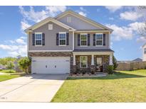 Charming two-story home with gray siding, stone accents, black shutters, and a well-manicured front yard at 411 Lawton Dr, Haw River, NC 27258