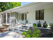 Inviting front entrance featuring a light blue door, stone steps, and elegant landscaping at 4902 Brookhaven Dr, Raleigh, NC 27612
