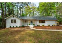 Charming single-story home with a white brick facade, a light blue front door, and well-maintained landscaping at 5312 Woodsdale Rd, Raleigh, NC 27609