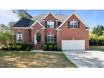 Traditional red brick two-story home with a well-manicured lawn and a two-car garage at 5408 Colonial Oaks Dr, Apex, NC 27539