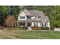 Charming two-story home with stone accents, lush landscaping, and inviting front porch at 64 Thousand Oaks Ct, Clayton, NC 27527