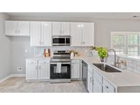 Bright kitchen features white cabinetry, stainless steel appliances, and marble countertops at 6863 Paint Rock Ln, Raleigh, NC 27610