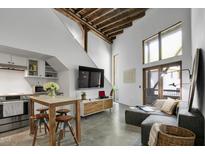 Bright living room featuring a modern table, wood beams, and a large window at 701 W Trinity Ave # 116, Durham, NC 27701