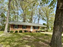 Charming brick home with manicured lawn and mature trees offers classic curb appeal at 1031 Jackson Royster Rd, Henderson, NC 27537