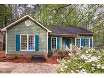 Charming single-story home featuring a well-maintained yard, complemented by green siding and teal-colored window shutters at 13 Thorne Ridge Dr, Durham, NC 27713