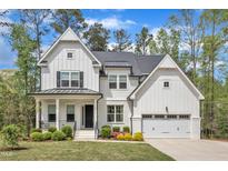 Stunning new construction farmhouse with a two-car garage, white siding, and a beautifully landscaped lawn at 2432 Spindle Ct, Raleigh, NC 27603